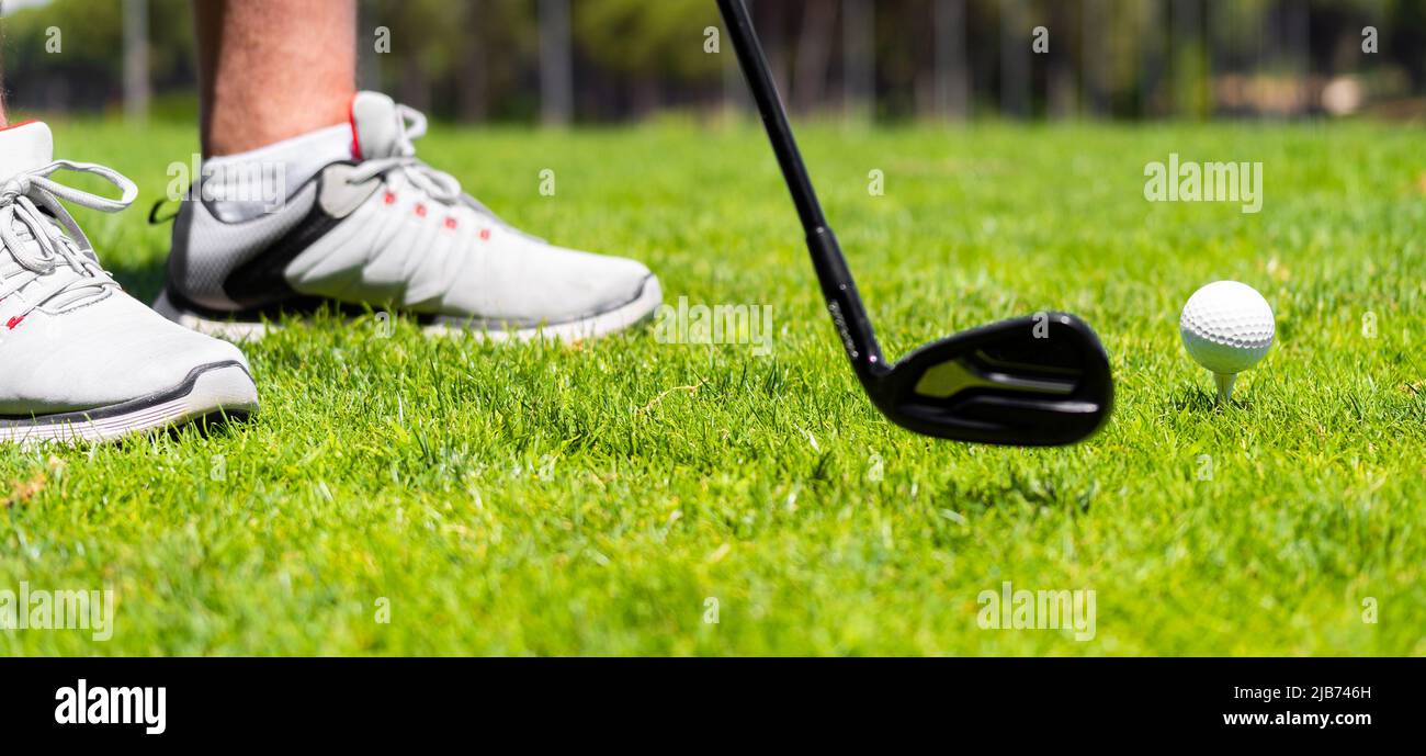 Mann, der mit einem eisernen Golfschläger steht, bereit, auf dem Golfplatz einen Ball auf grünem Gras zu schlagen Stockfoto
