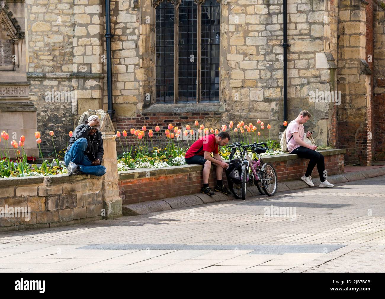 Drei Männer an der Wand mit Mobiltelefonen St Benedicts Square Licoln 2022 Stockfoto