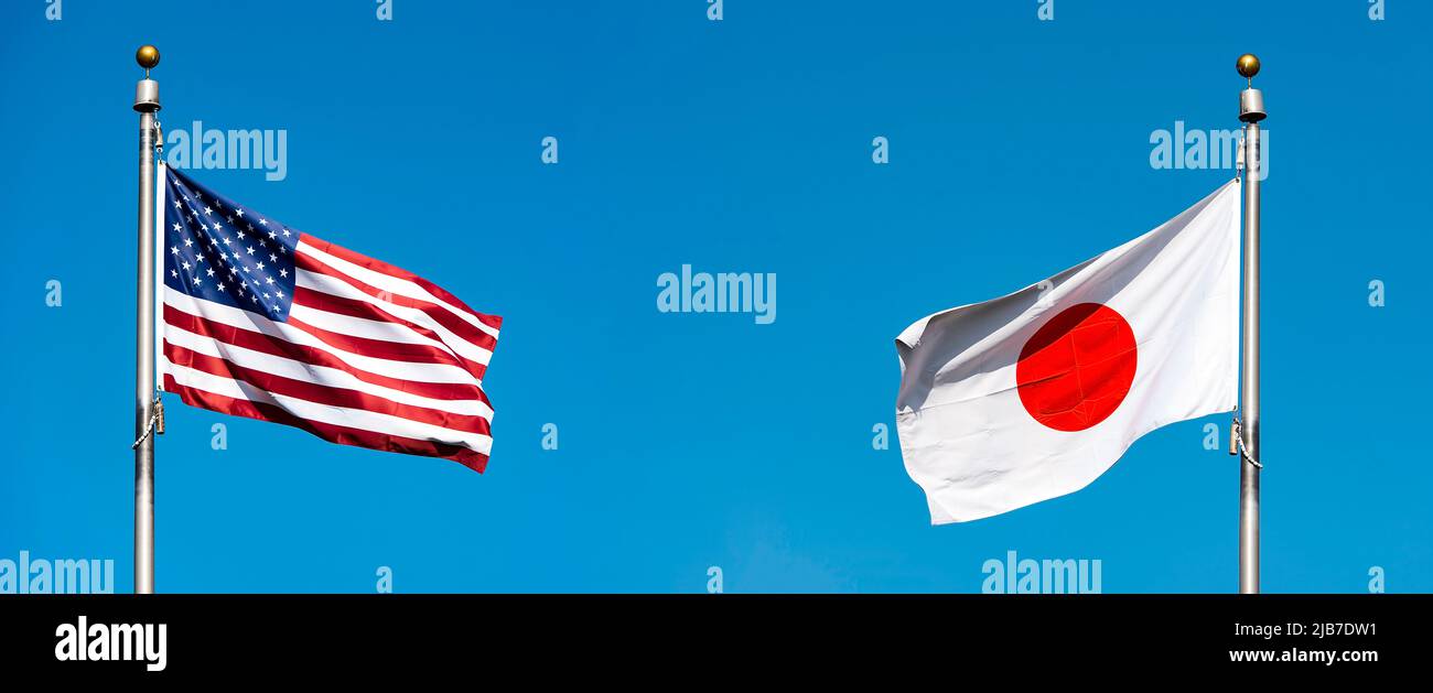 Flaggen der USA und Japans gegen blauen Himmel, konzeptuelle politische Abbildung Stockfoto