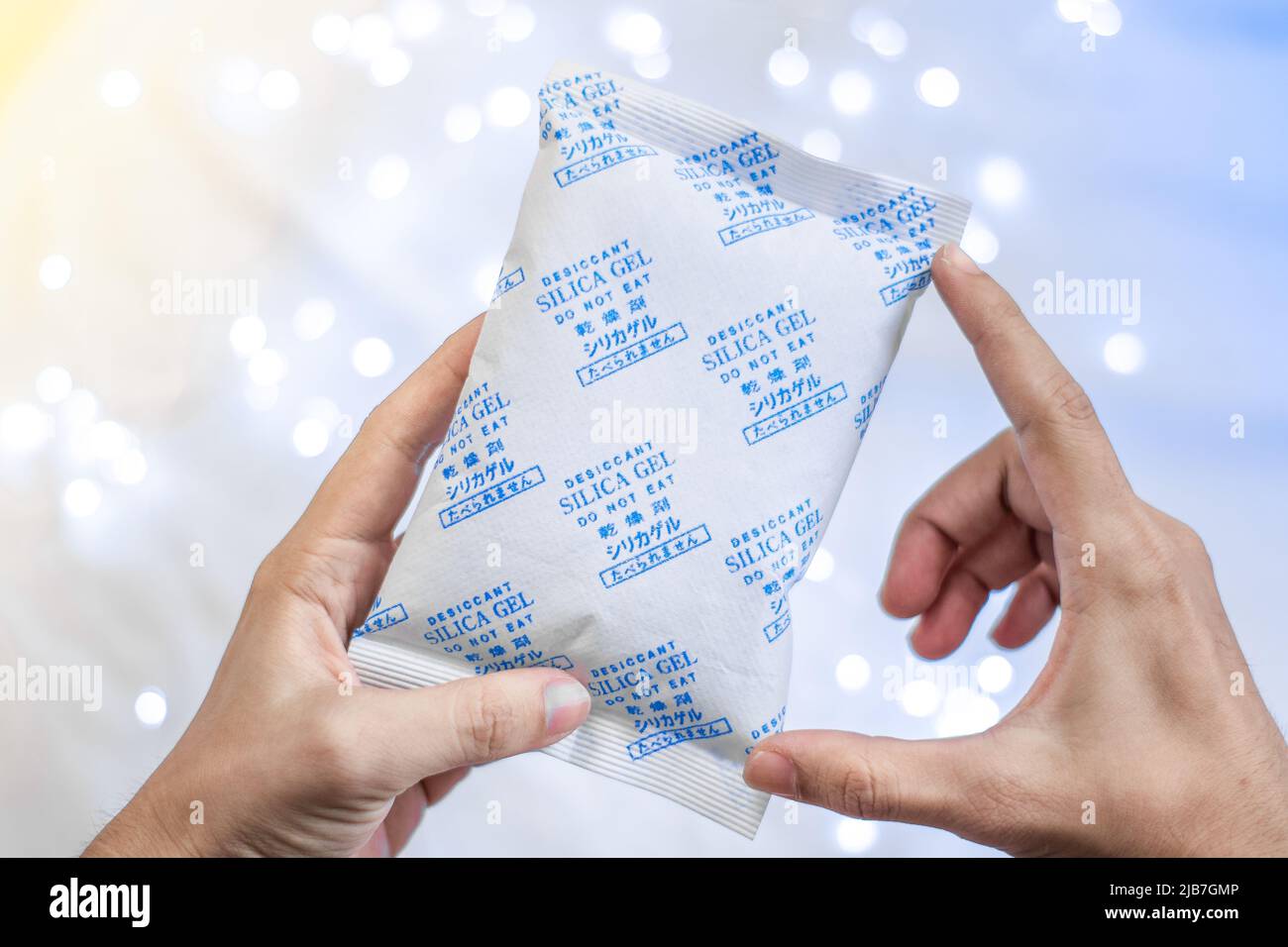 Trockenmittel-Silica-Gelbeutel mit weißem, hellem Hintergrund auf der Hand Stockfoto