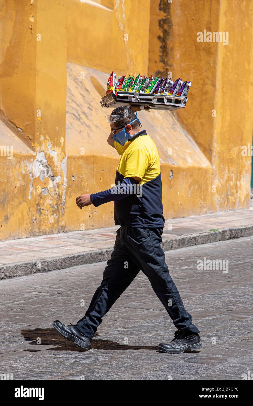 Ein Mann, der über die Straße ging und ein Tablett mit Chips trug. San Miguel de Allende, Mexiko. Stockfoto