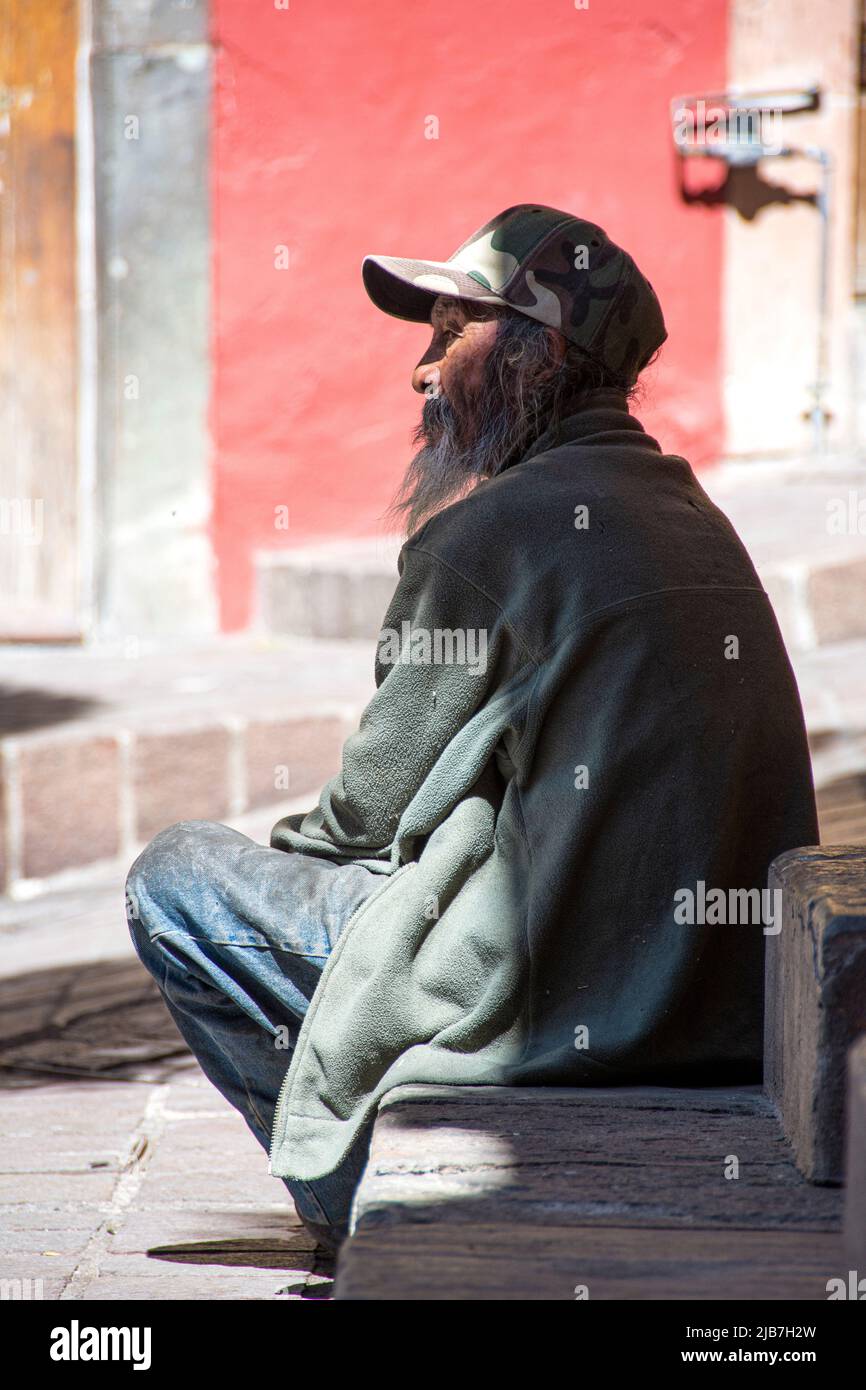 Ein mexikanischer Mann asiatischer Abstammung sitzt neben einem Brunnen in einem der zahlreichen Plätze von Guanajuato, Mexikos zahlreichen Plätzen, Menschen watching.in Stockfoto