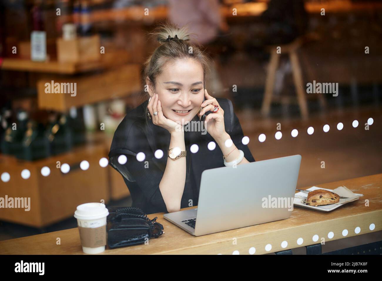 asiatische Frau, die mit einem Laptop im Café arbeitet Stockfoto