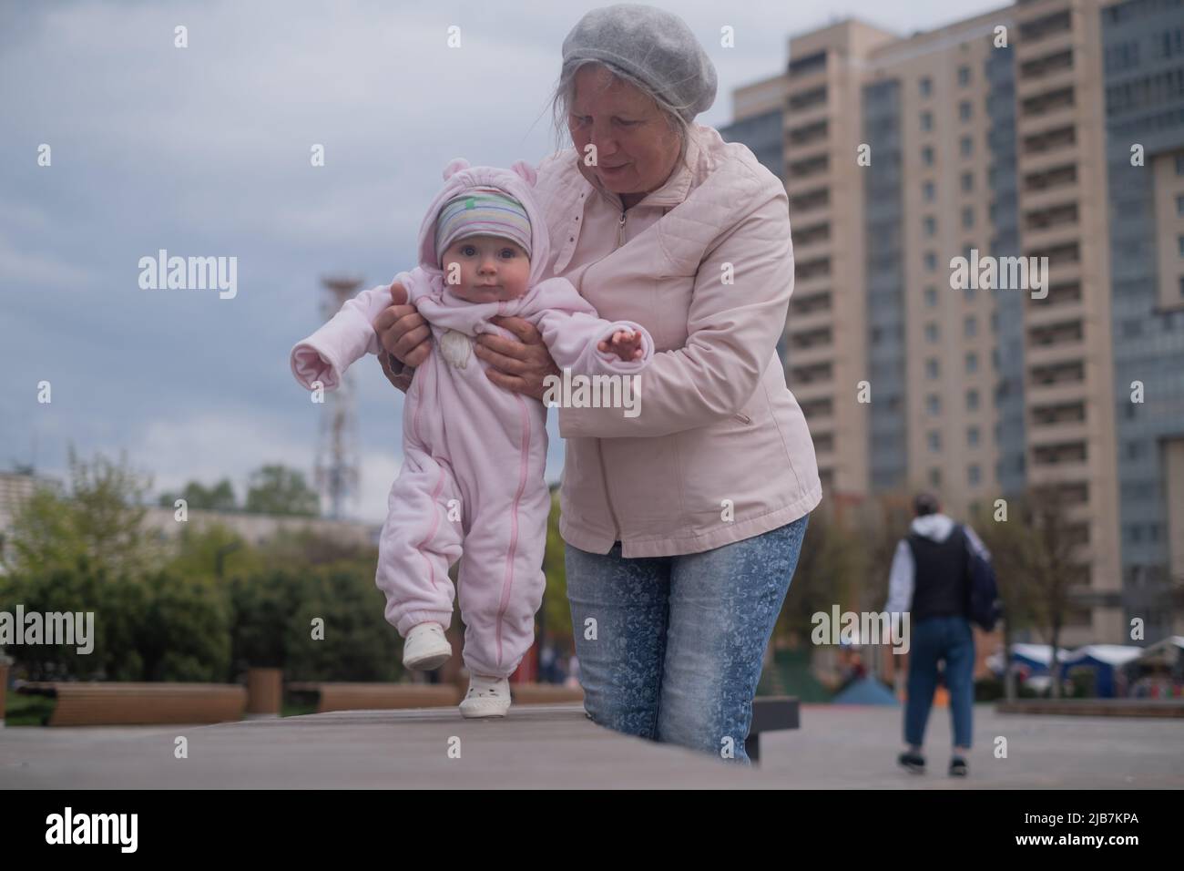 Kleines Mädchen, das mit einer Frau im Freien läuft. Großmutter hilft Enkelin zu gehen Stockfoto