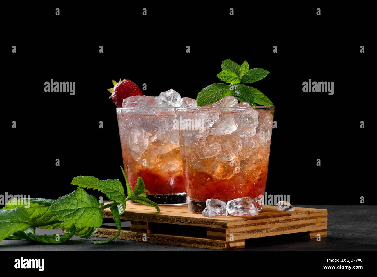 Kalter Sommer Erdbeer Eiscocktail Mojito, margarita, Daiquiri in zwei Gläsern mit Minzblättern auf dunklem Grund Stockfoto