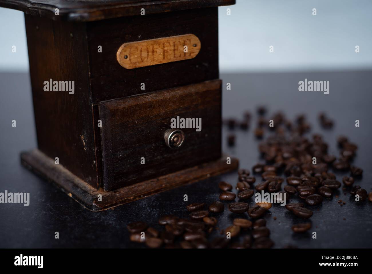 Nahaufnahme der Vintage Kaffeemühle mit Bohnen auf dunkelschwarzem und grauem Hintergrund. Schärfentiefe. Holz und Eisen. Stockfoto