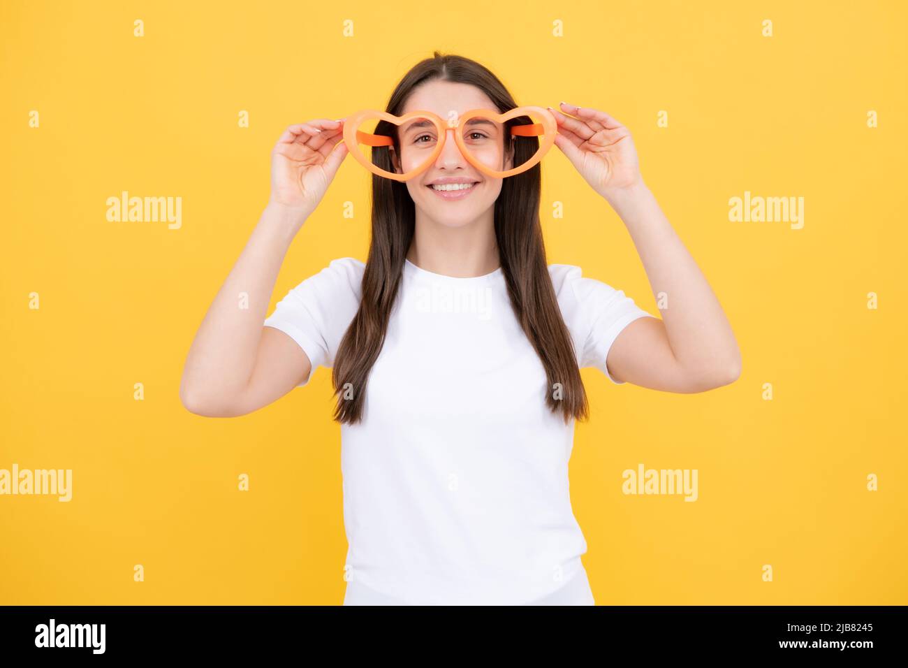 Mädchen mit herzförmigen Gläser lustig und lächelnd auf gelben Studio-Hintergrund. Stockfoto