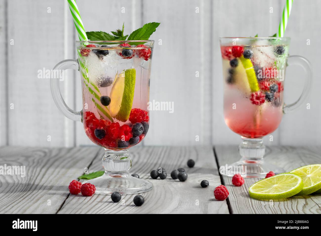 Frische hausgemachte Sommercocktails mit Eis, Limette und Beeren in Gläsern mit Strohhalm Stockfoto