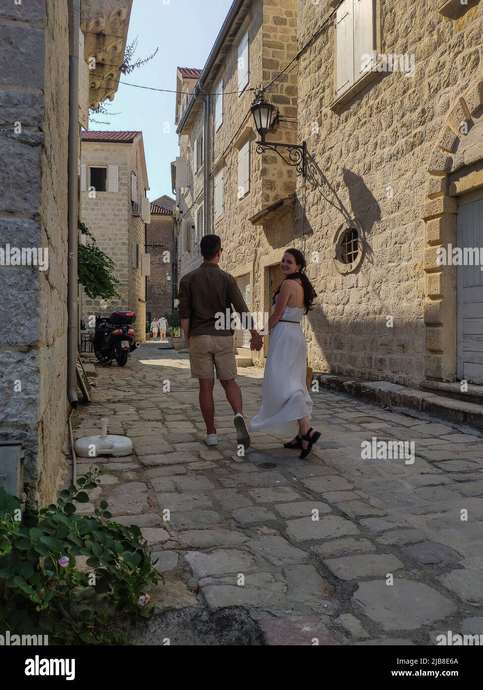 In der Altstadt von Kotor, Montenegro, läuft ein schönes Paar in einer engen Straße mit Topfpflanzen Stockfoto