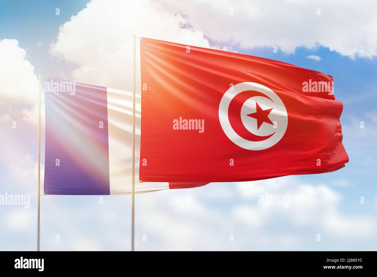 Sonniger blauer Himmel und Flaggen von tunesien und frankreich Stockfoto