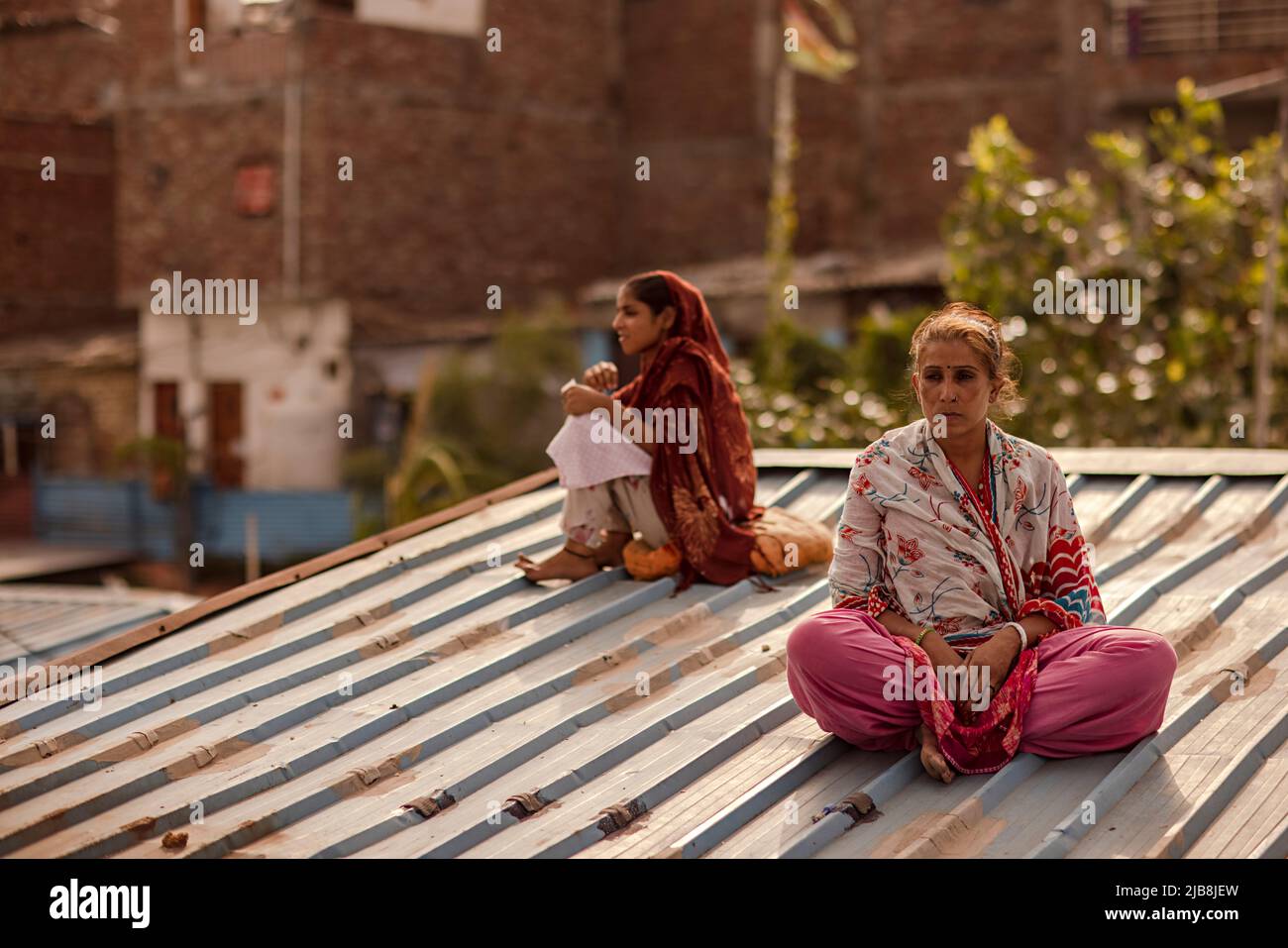 Eine Frau mittleren Erwachsenen, die mit einem Teenager-Mädchen auf dem Dach sitzt Stockfoto