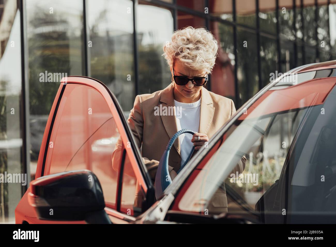 Ernsthafte Frau versucht, Schlüssel zu ihrem Auto in der Tasche zu finden Stockfoto