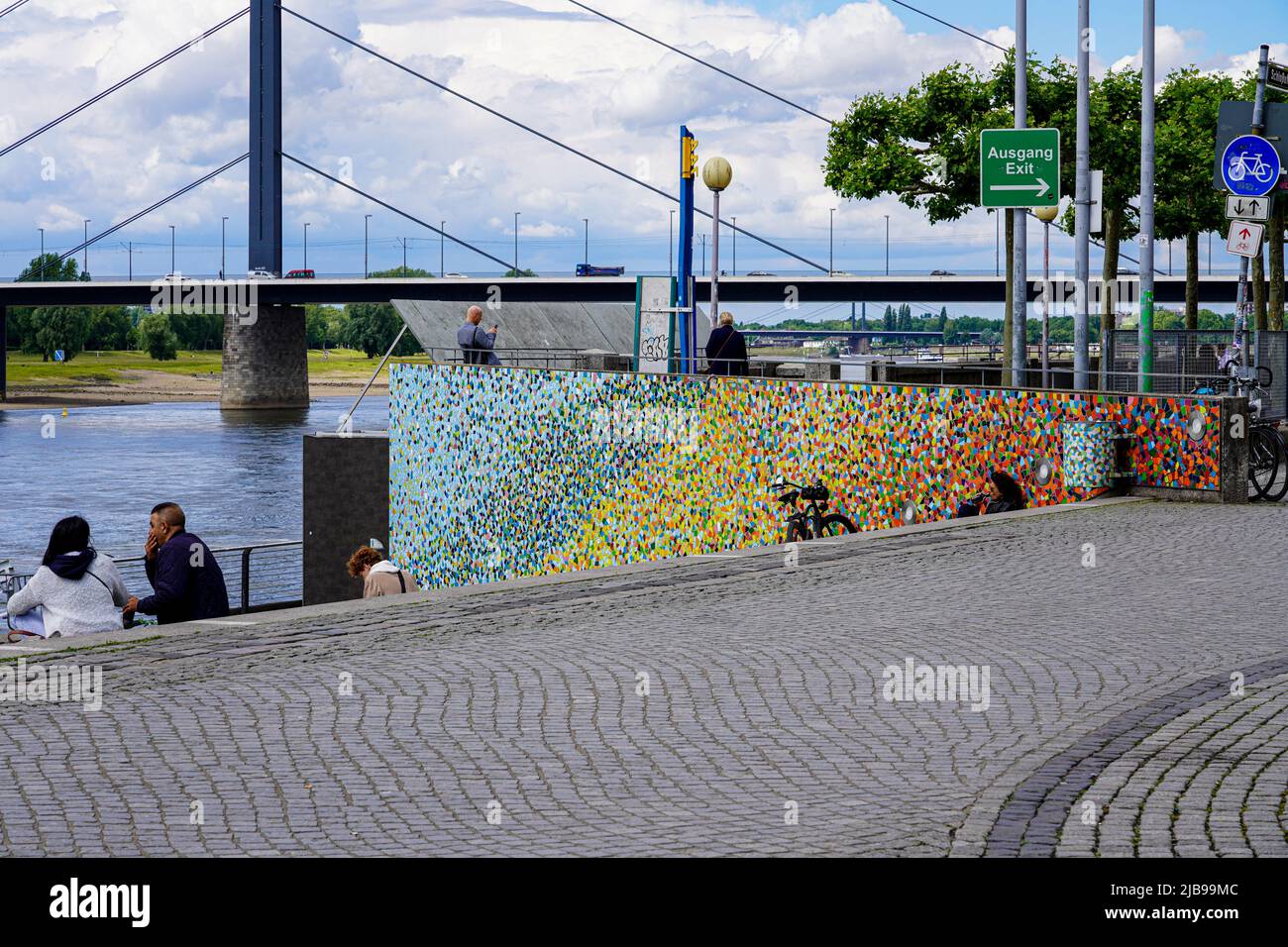 Menschen sitzen an der Fliesenkunst Rivertime von Hermann-Josef Kuhna am Rheinufer. Düsseldorf, Nordrhein-Westfalen, 24,5.22. Stockfoto