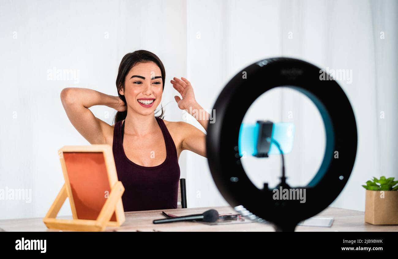 Junge Frau vloggt online mit Smartphone Cam und Ring von zu Hause aus geführt - Millennial Menschen mit Social Media und Smart Working Konzept Stockfoto