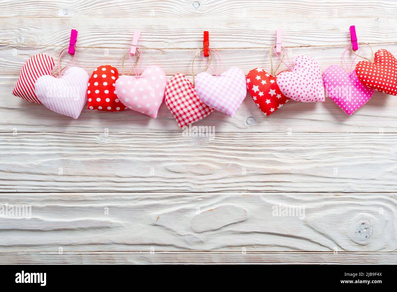 Valentine Stoffherzen an Seil auf weißem Holzhintergrund gehängt Stockfoto