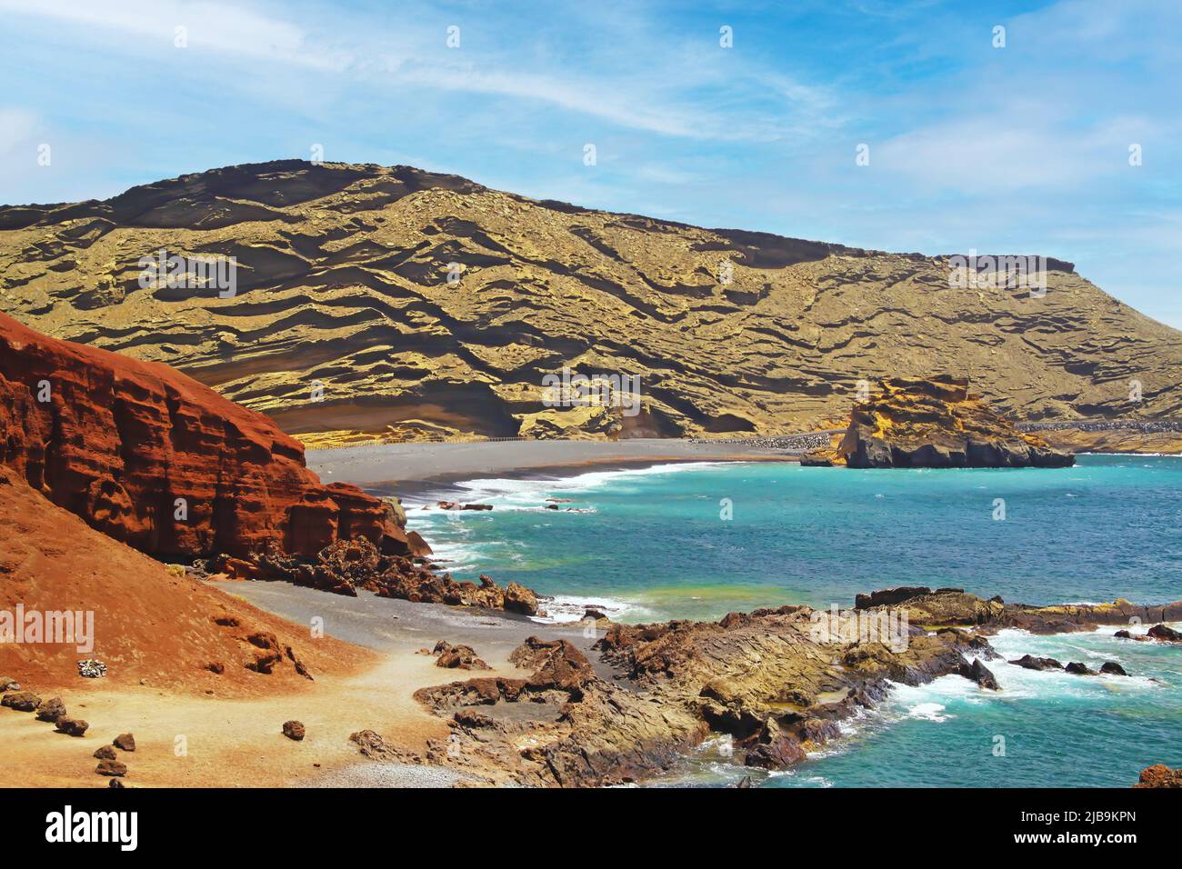 Wunderschöne, abgeschiedene Lagune, umgeben von beeindruckenden, zerklüfteten, verwitterten Klippen, verschiedenen Farben, roten Felsen, leerstem, schwarzen Sandstrand - El Golfo, La Stockfoto