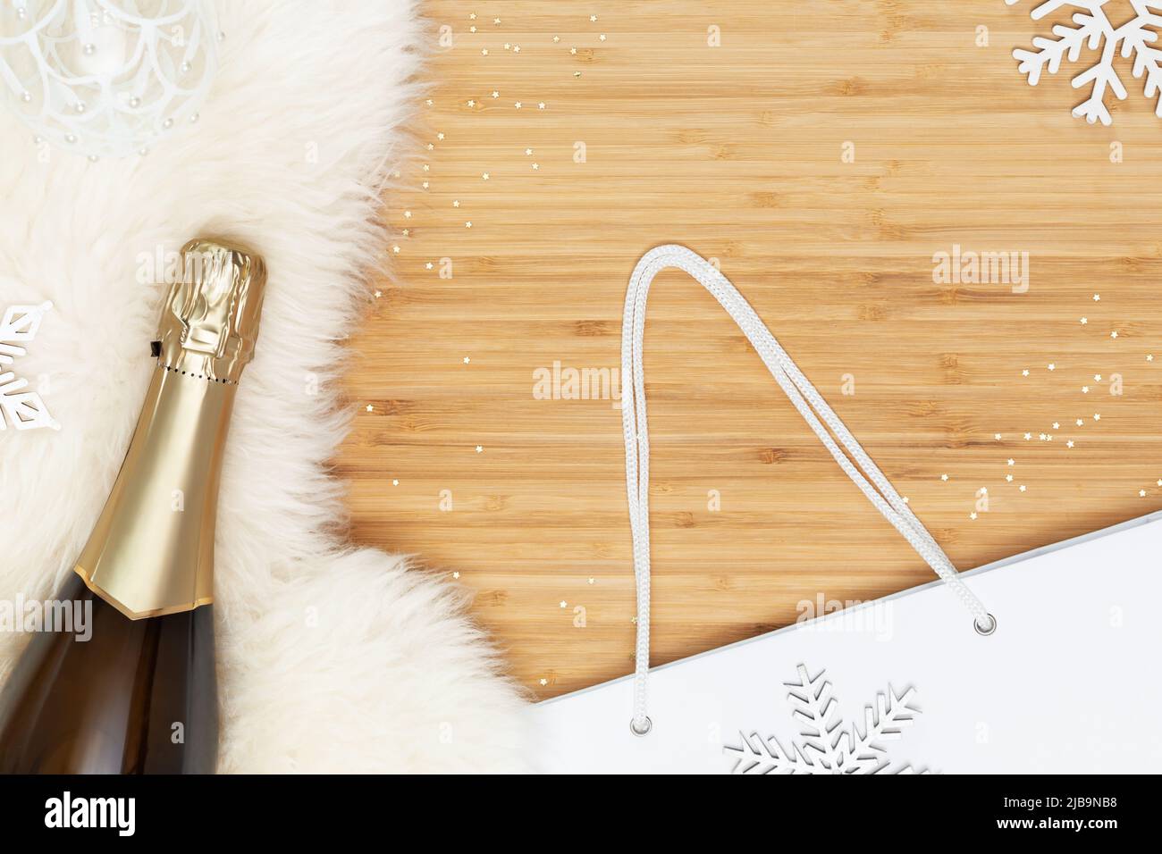 Flasche Champagner auf einem weißen Pelzteppich mit weißer Geschenktüte Stockfoto