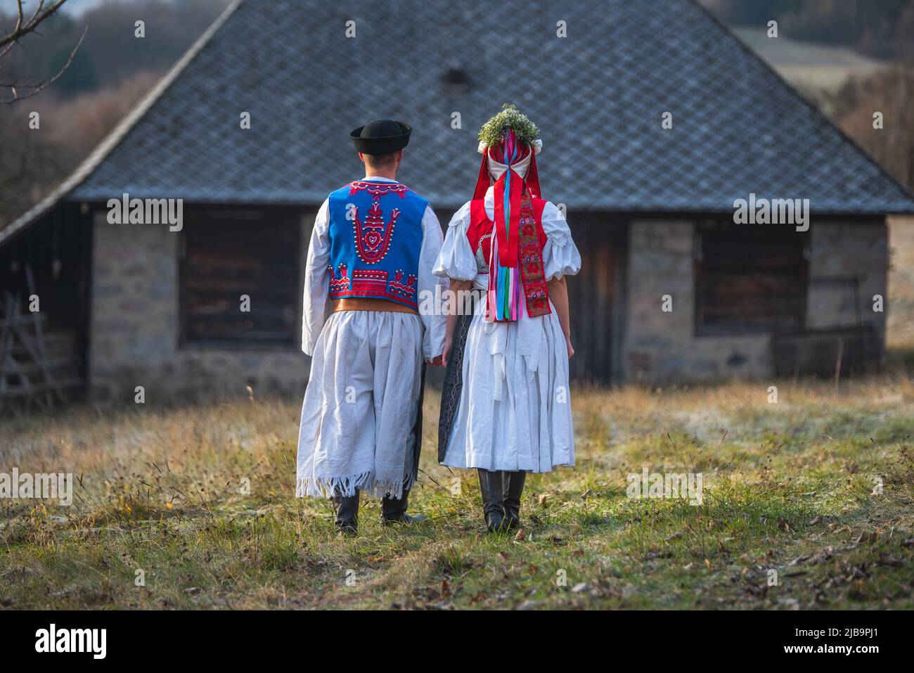 Ein Paar in traditioneller Tracht. Slowakische Kostüm im Herbst Natur. Altes Landhaus im Hintergrund. Junges Paar in Tracht Wal Stockfoto