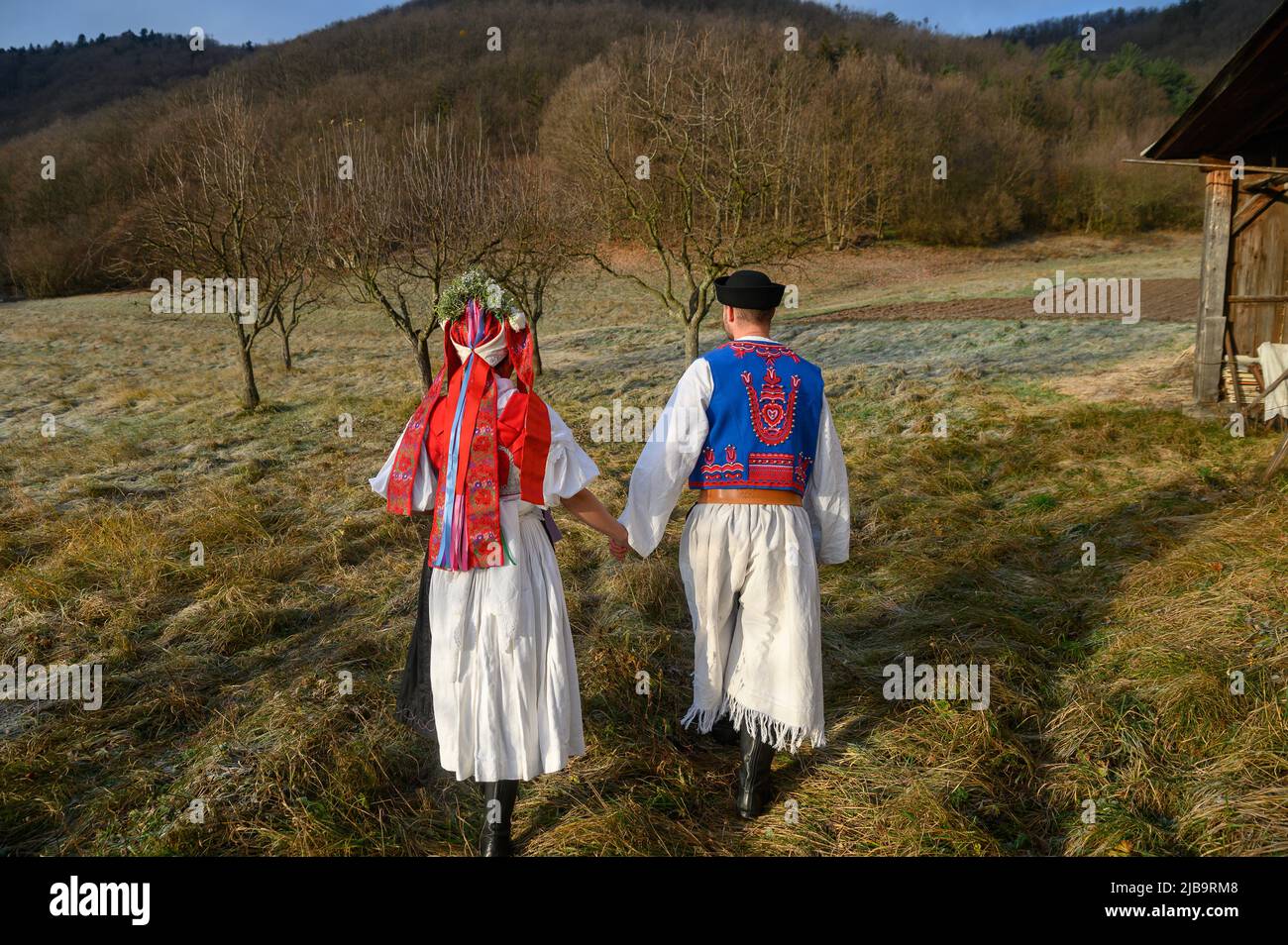 Ein Paar in traditioneller Tracht. Slowakische Kostüm im Herbst Natur. Altes Landhaus im Hintergrund. Junges Paar in Tracht Wal Stockfoto