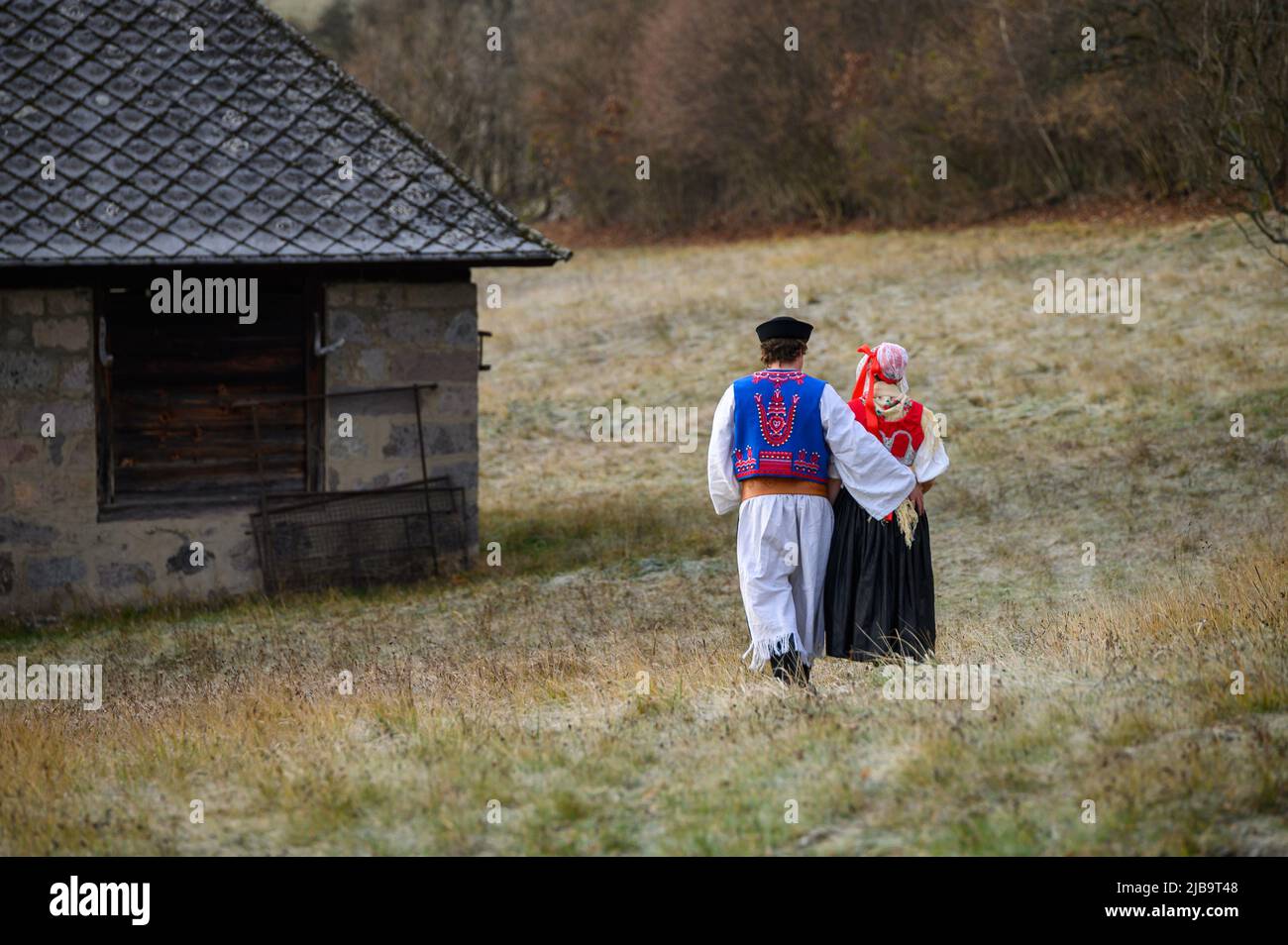 Ein Paar in traditioneller Tracht. Slowakische Kostüm im Herbst Natur. Altes Landhaus im Hintergrund. Junges Paar in Tracht Wal Stockfoto