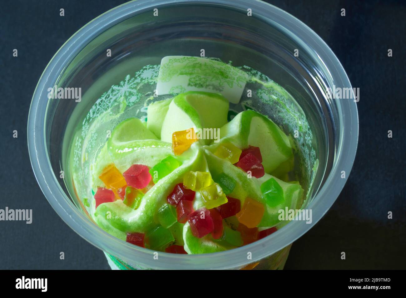 Süßes Eis in einem Plastikbecher auf dem Tisch. Essen auf dunklem Hintergrund Stockfoto