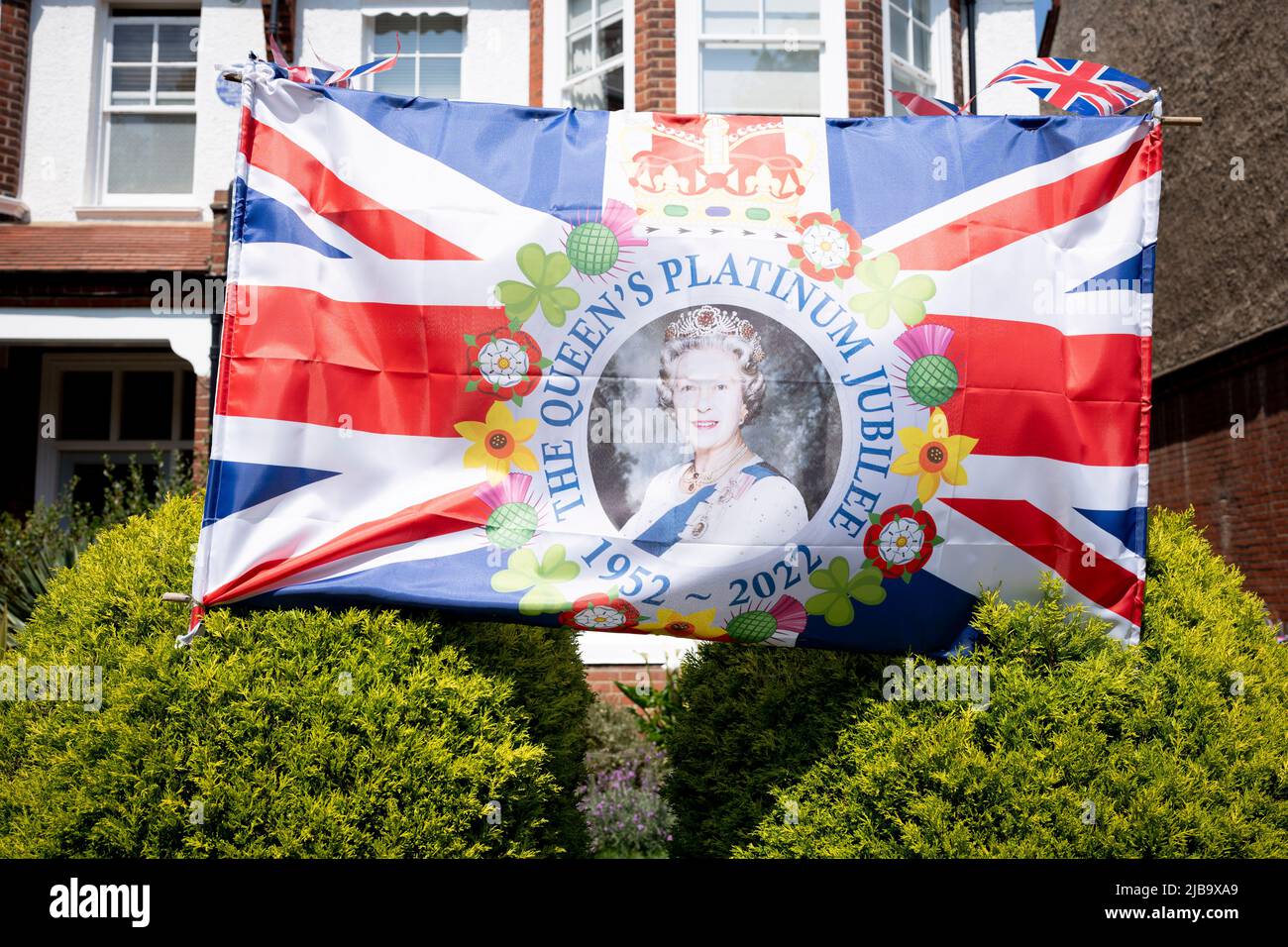 Das Gesicht der Königin lächelt Passanten aus dem Vorgarten eines Wohnhauses in Dulwich während des Long Bank Holiday Weekends zur Feier des Platin-Jubiläums der Königin am 4.. Juni 2022 in London, England, an. Königin Elizabeth II. Steht seit 70 Jahren auf dem britischen Thron, der dienstältesten Monarchin der englischen Geschichte, und während des Jubiläumswochenendes organisiert die Öffentlichkeit Straßenfeste und Gemeindeveranstaltungen. Stockfoto