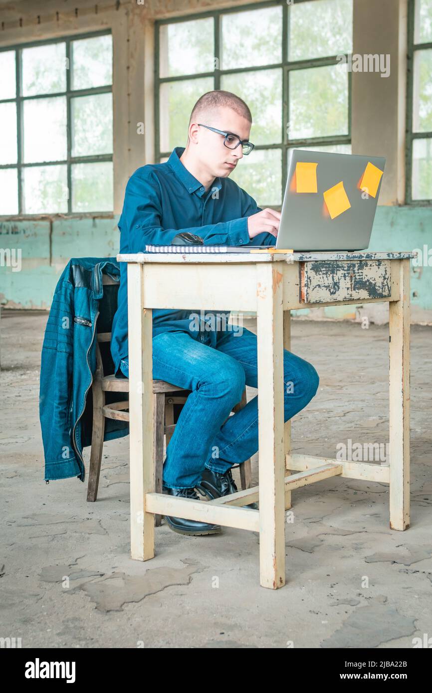 Foto eines Studenten in blauem Hemd mit einem Laptop vor ihm, der sich auf die Prüfung vorbereitete. Stockfoto