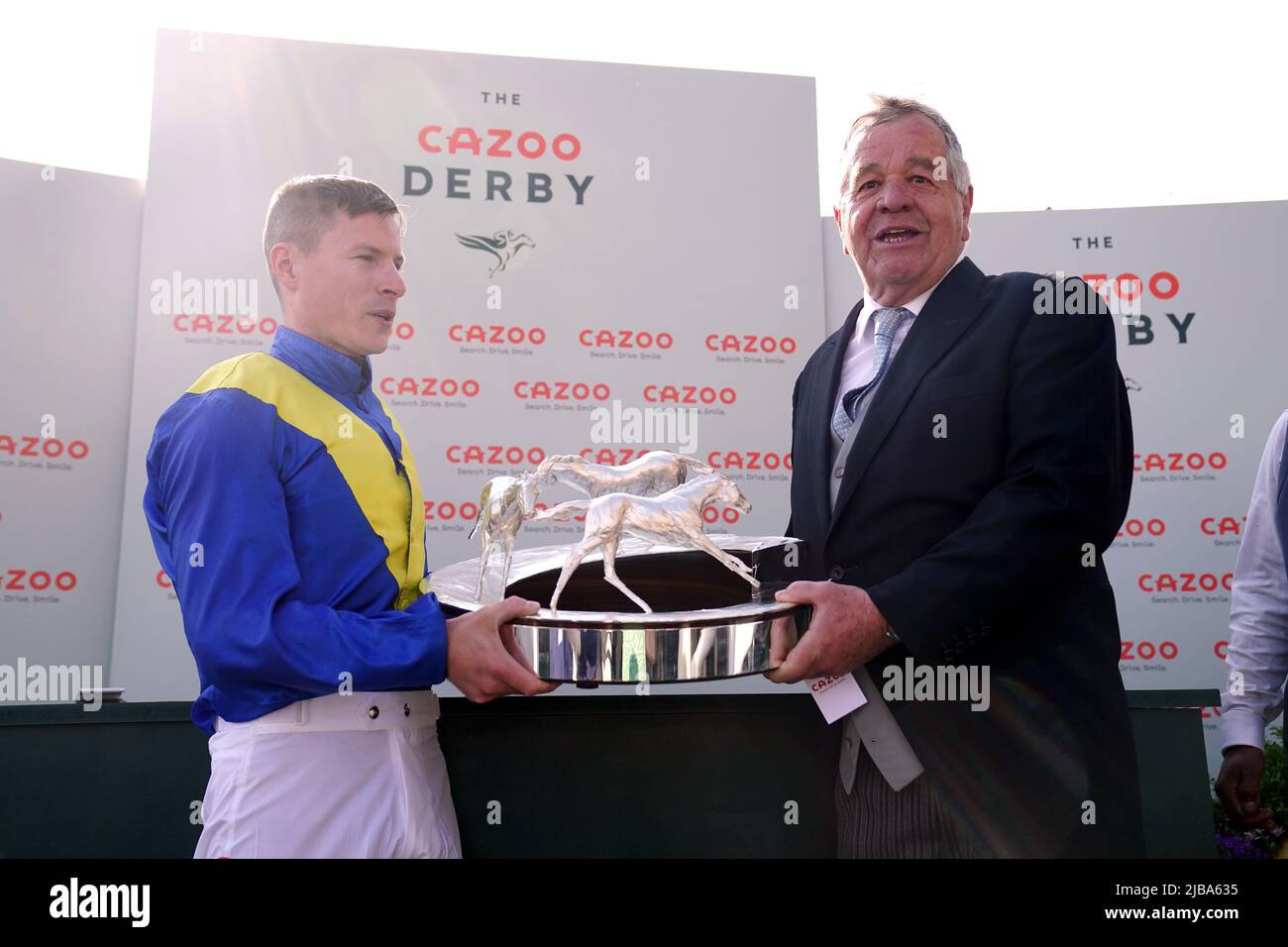Jockey Richard Kingscote und Trainer Sir Michael Stoute mit der Trophäe nach dem Gewinn des Cazoo Derby (in Erinnerung an Lester Piggott) mit Desert Crown am Derby Day während des Cazoo Derby Festivals 2022 auf der Epsom Racecourse, Surrey. Bilddatum: Samstag, 4. Juni 2022. Stockfoto
