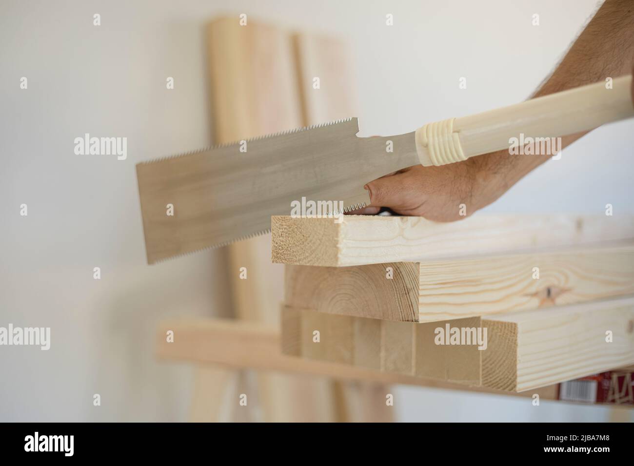 Männliche Hände mit einer traditionellen japanischen Metallschreinersäge (ryoba) mit einer Doppelsäge, die ein Stück Holz in einer Zimmerei schneidet Stockfoto