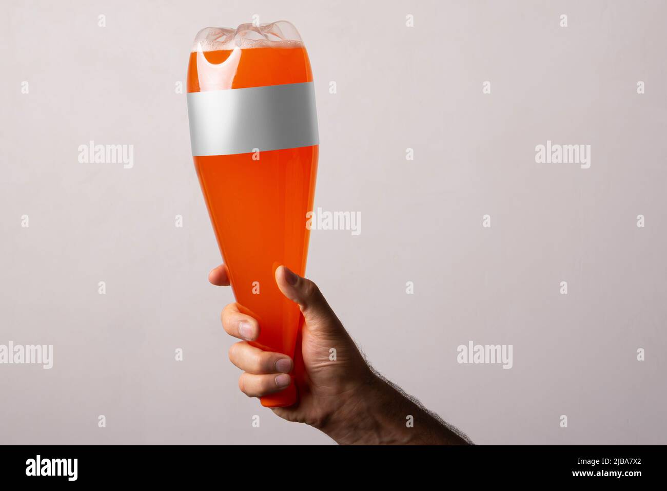 Orange Soda Plastikflasche bei männlichen Hand isoliert auf grauem Hintergrund, bearbeitbare Modell-up-Serie Vorlage bereit für Ihr Design, Flasche Label Auswahl pa Stockfoto