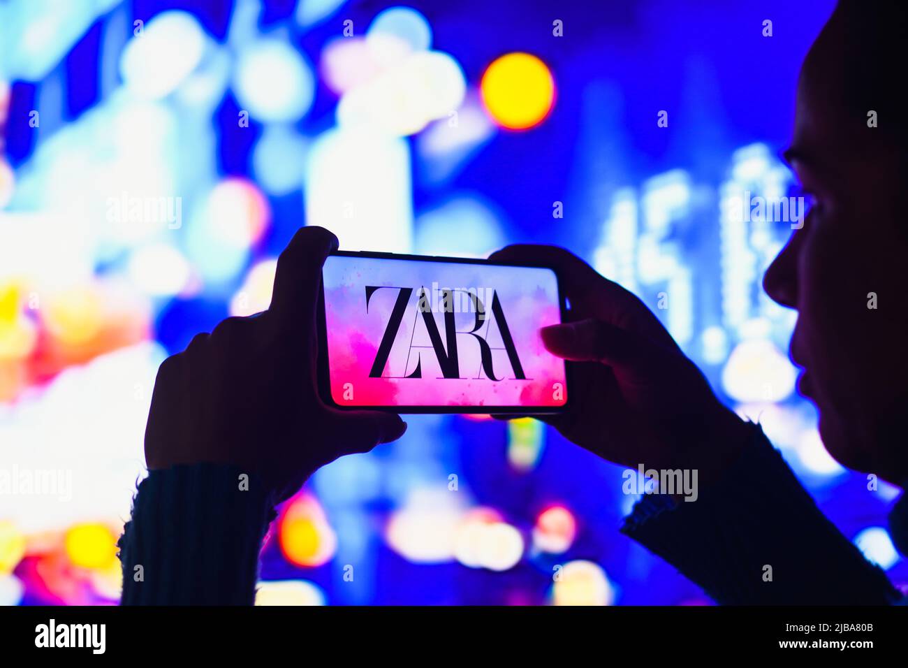 In dieser Abbildung hält ein silhouettierter Mensch ein Smartphone mit dem Zara-Logo auf dem Bildschirm. Stockfoto