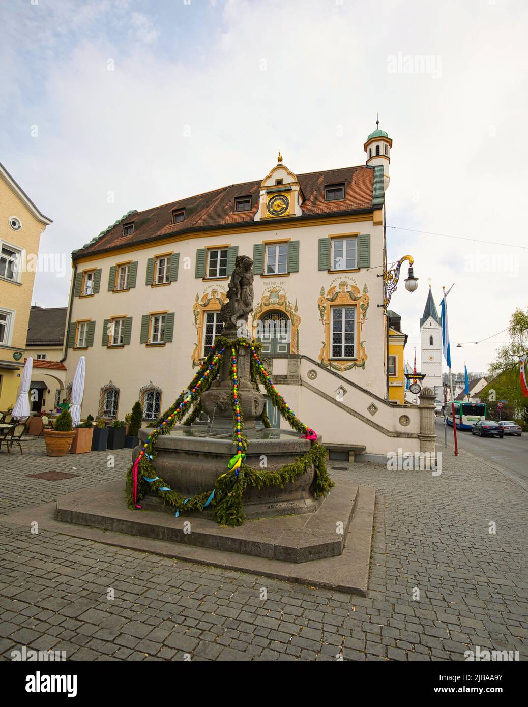 Fürstenfeldbruck, Bayern, Deutschland - 23. April 2022: Geschmückter Kriegerbrunnen und altes Rathaus mit St. Leonhard Kirche im Hintergrund. Stockfoto