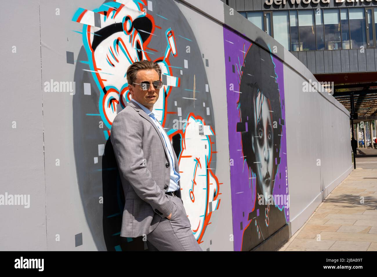 Ipswich Suffolk UK May 27 2022: Ein hübscher Geschäftsmann in einem grauen Anzug vor einigen städtischen Kunstwerken Stockfoto