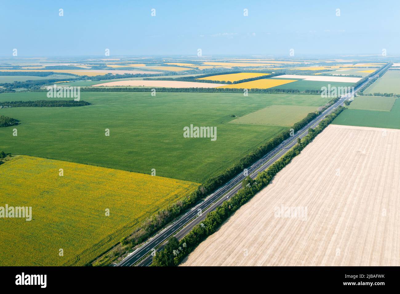 Landwirtschaftliche Flächen: Flächen verschiedener landwirtschaftlicher Felder aus großer Höhe: Grüne, gelbe Felder sind durch eine Autobahn getrennt. Landwirtschaft in einem Agrarland - Drohnenaufnahme von Plantagen. Stockfoto