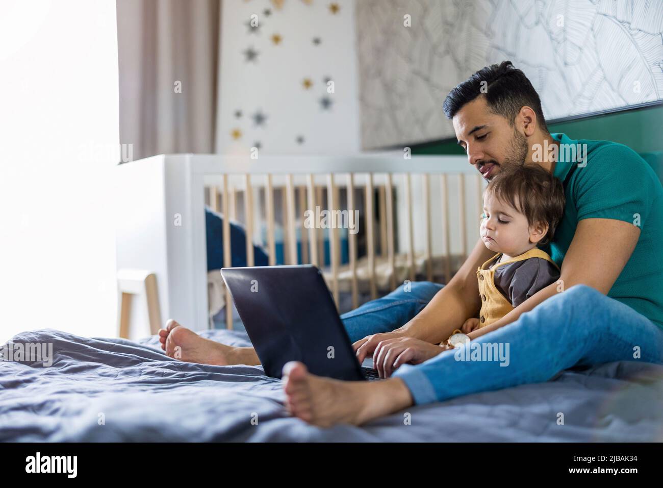 Der junge Mann und sein Sohn verwenden zu Hause einen Laptop Stockfoto