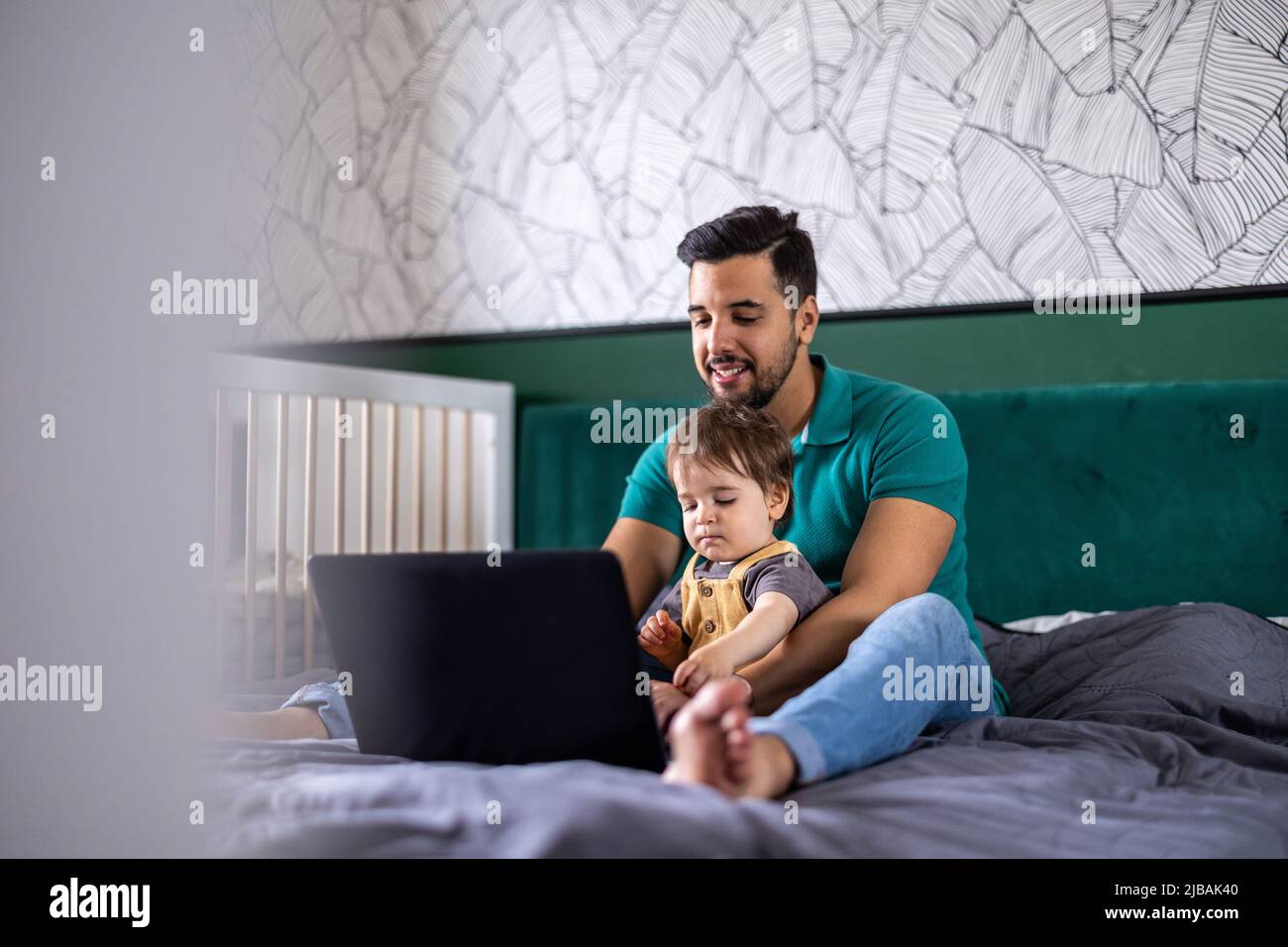 Der junge Mann und sein Sohn verwenden zu Hause einen Laptop Stockfoto