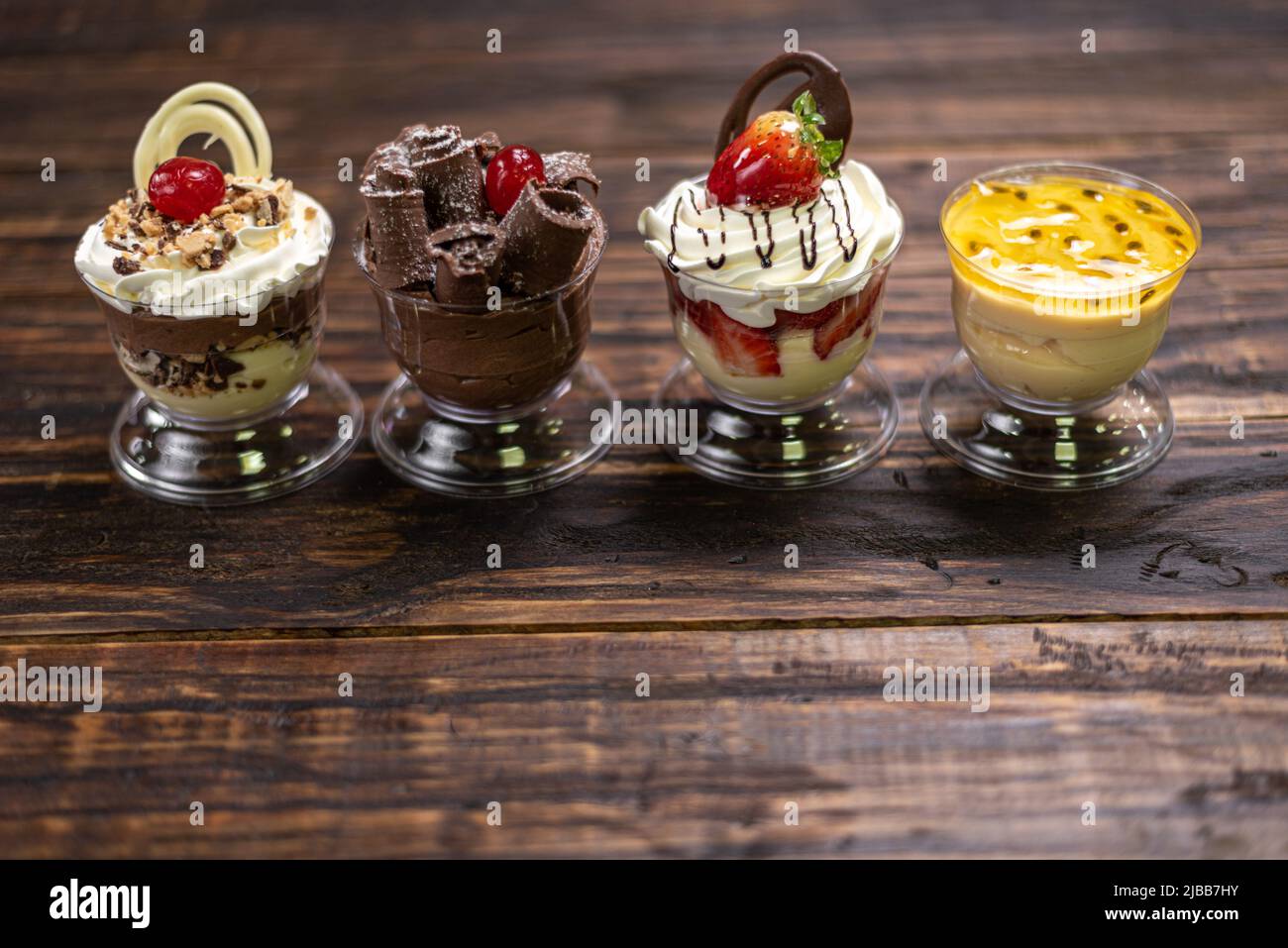 Auswahl an Desserts . Passionsfrucht, Schokolade, Erdbeermousse auf Holzhintergrund Stockfoto