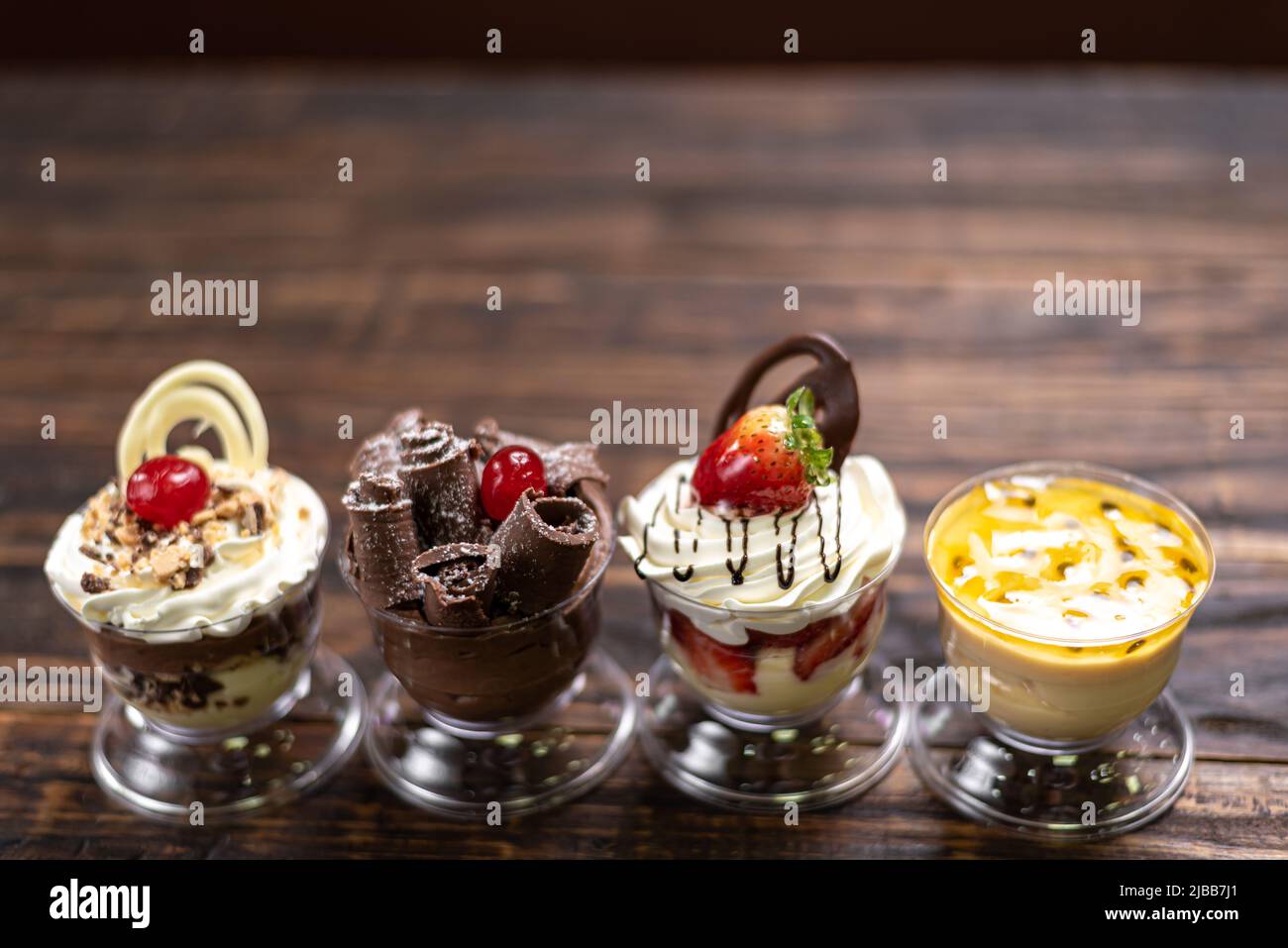 Auswahl an Desserts . Passionsfrucht, Schokolade, Erdbeermousse auf Holzhintergrund Stockfoto