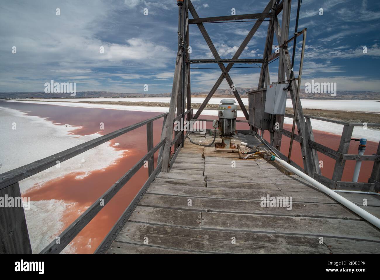 Eine hölzerne Plattform und Pumpe in einer landschaftlich schönen Lage über einem Salzverdampfungsteich. Stockfoto