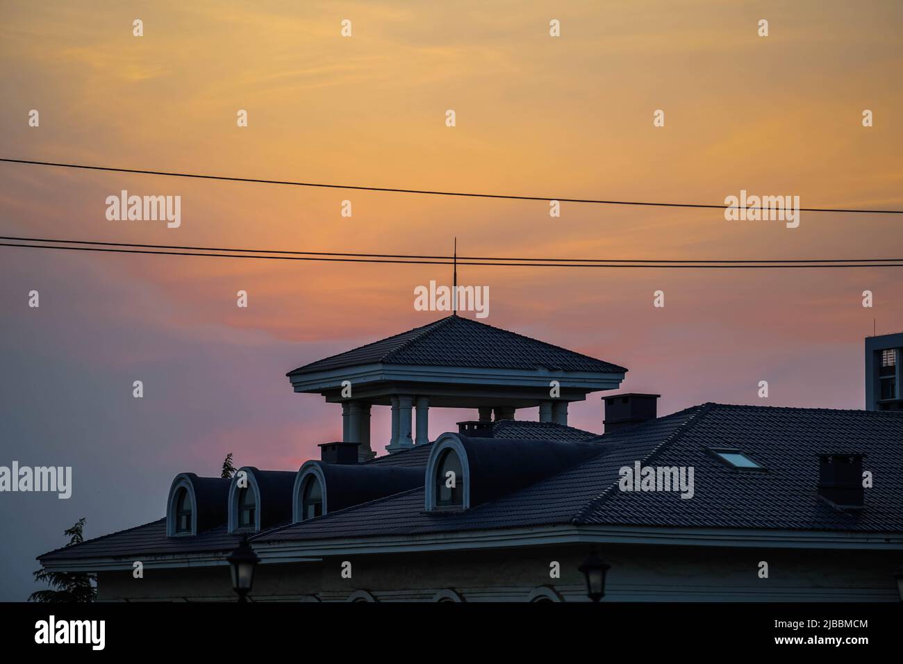 Sonnenuntergang, Pavillion Gebäude, goldener Sonnenuntergang, Stromleitungen Stockfoto