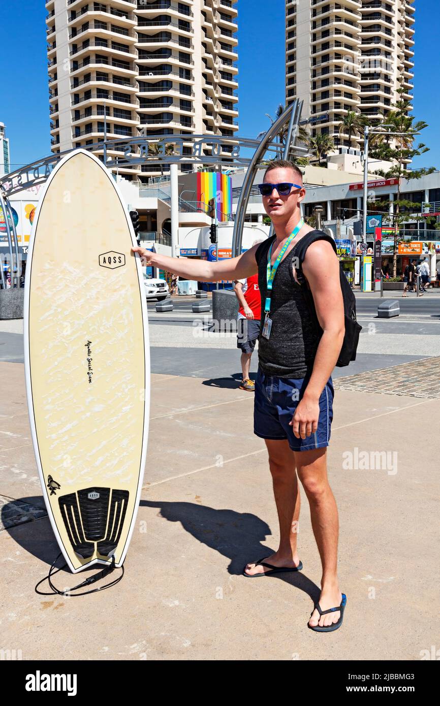 Queensland Australien / Ein junger männlicher Tourist posiert mit seinem Surfboard in Surfers Paradise Beach. Stockfoto