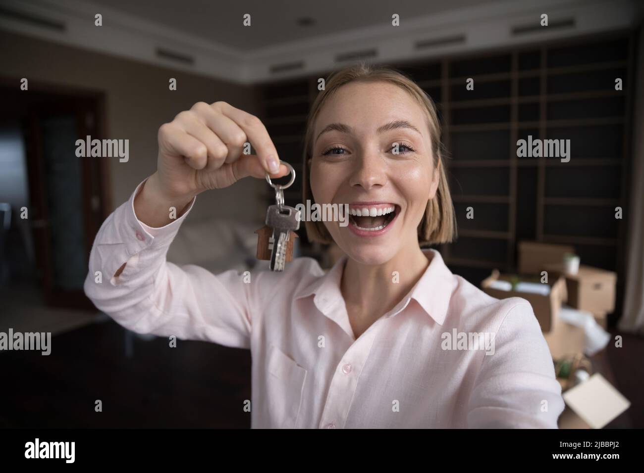 Glückliche weibliche neue Mieter der Wohnung zeigt Schlüssel auf der Kamera Stockfoto