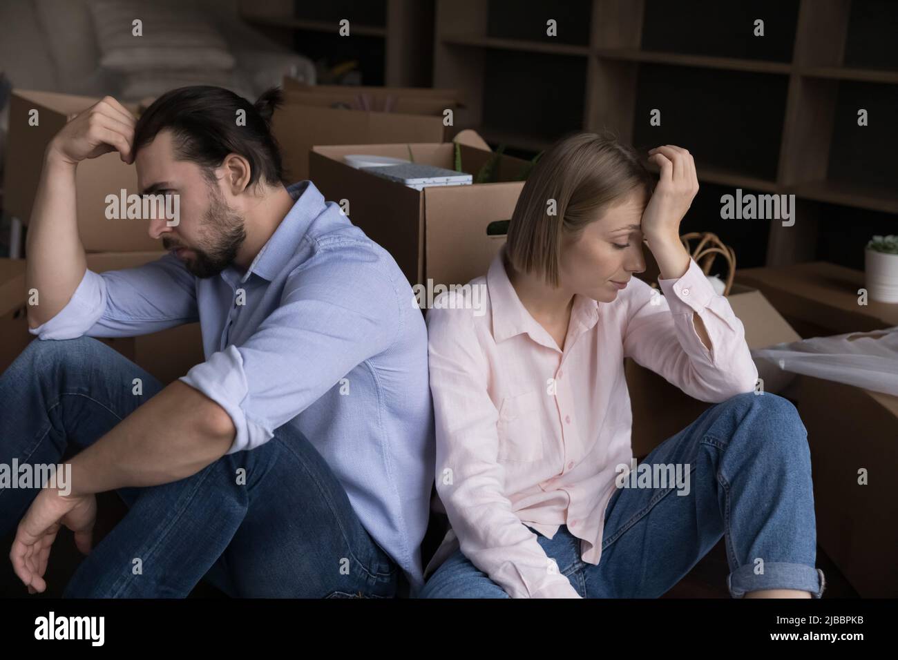 Unglückliches, müdes Paar sitzt auf dem Boden neben Kisten mit Sachen Stockfoto