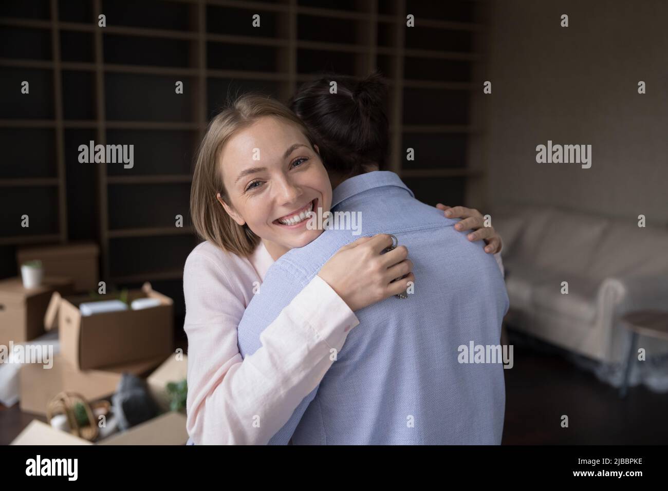 Frau umarmt geliebten Mann Blick auf die Kamera feiert Umzug Tag Stockfoto