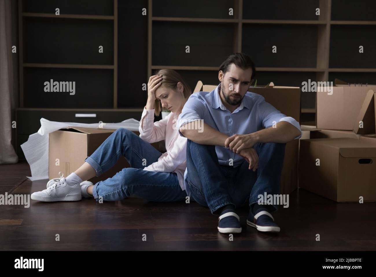 Müde verheiratete Paare sitzen auf dem Boden in der Nähe von Kartons Stockfoto