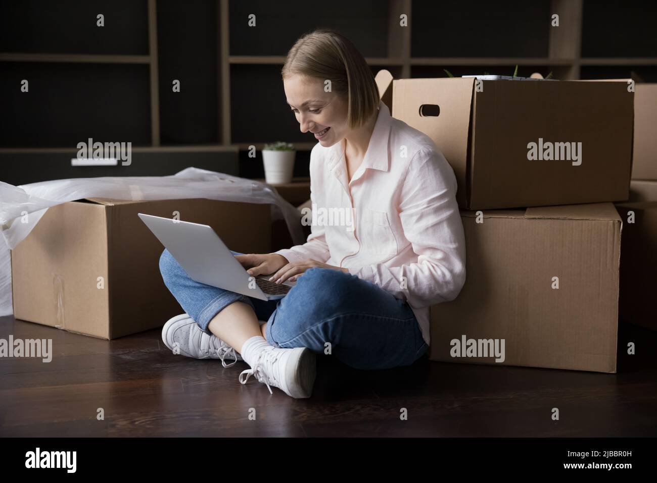 Frau mit Laptop bestellen, kaufen online am Umzugstag Stockfoto