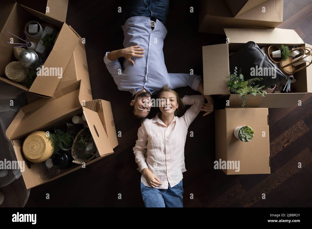 Ehepaar ruht sich am Umzugstag auf dem Boden in der Nähe von Kisten aus Stockfoto