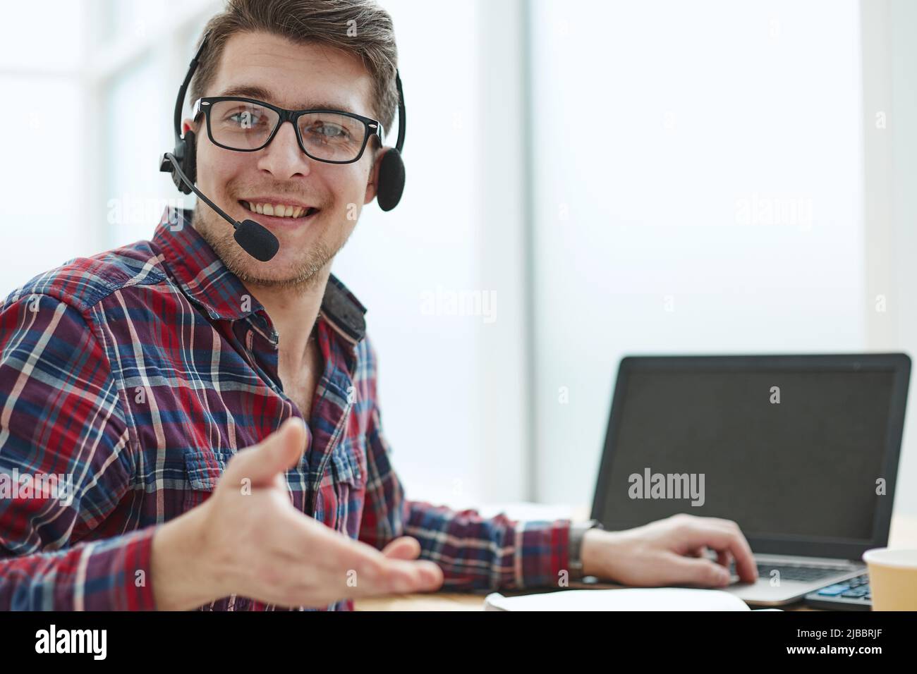 Porträt eines schönen männlichen Kundenservice in Kopfhörern. Callcenter-Mitarbeiter sprechen mit Kopf in einem modernen Büro Stockfoto
