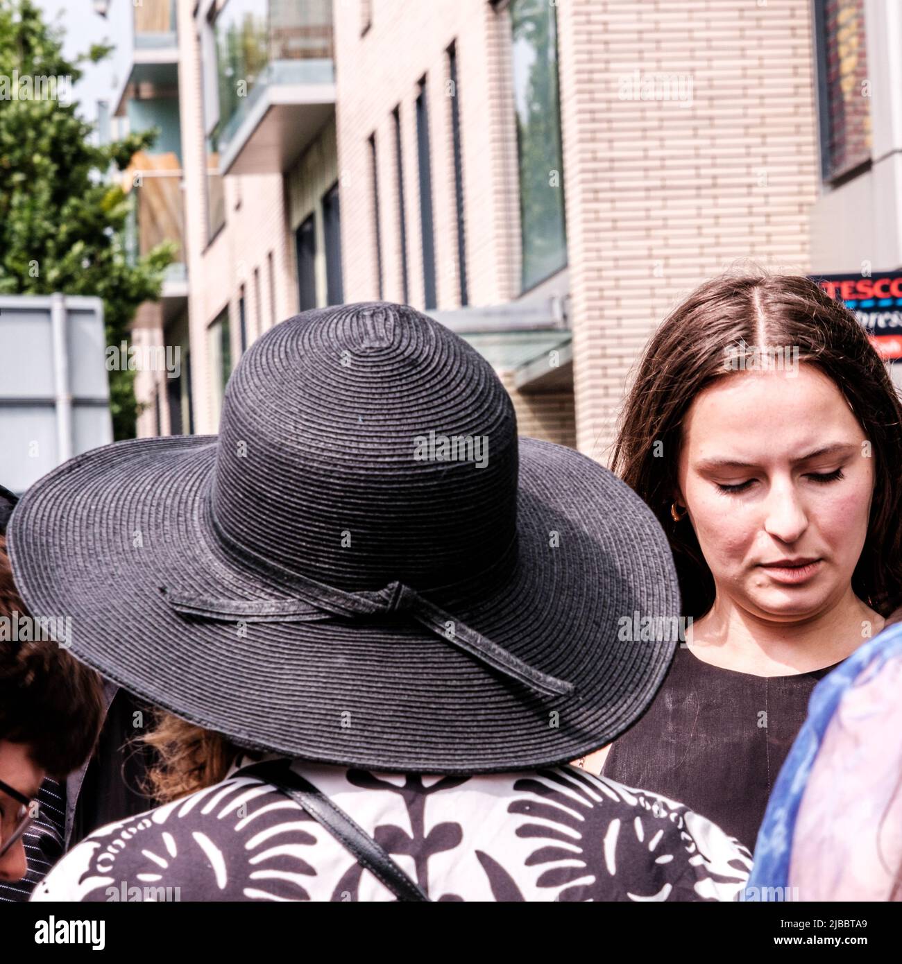 Epsom Surrey, London, Großbritannien, Juni 04 2022, Frau mit Back to Camera, die einen schwarzen Hut mit breitem Rand und eine gemusterte Jacke trägt Stockfoto