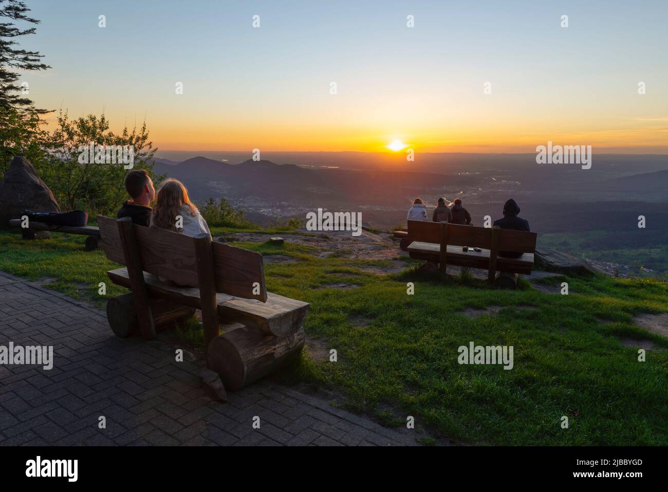 Besucher und Liebhaber der Teufelsmühle im Schwarzwald sitzen auf Bänken und beobachten den Sonnenuntergang über Murg und Rheintal Stockfoto